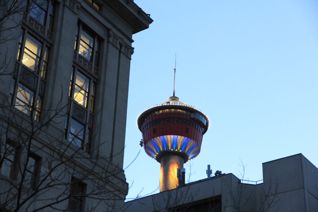 A picture of the Calgary Tower in the evening, framed above the buildings of Calgary